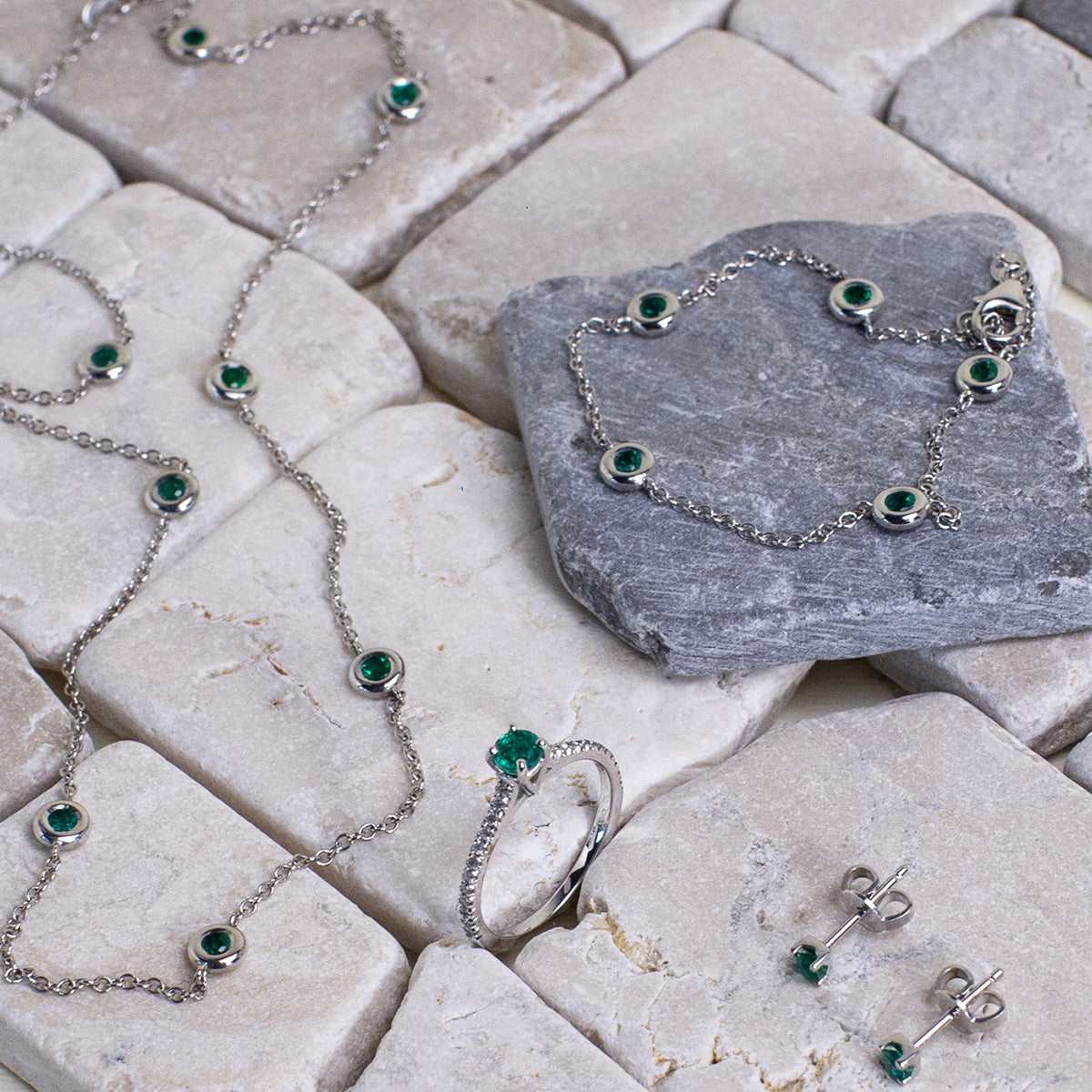 Modello indossa a Milano un set di gioielli esclusivi su tipiche lastre di pietra italiane, che ricordano che l'iconico è per sempre con Smeralco. Il set in oro bianco con smeraldi colombiani di Smeralco comprende anello, collana, bracciale e orecchini, esaltando la bellezza e l'eleganza senza tempo degli smeraldi